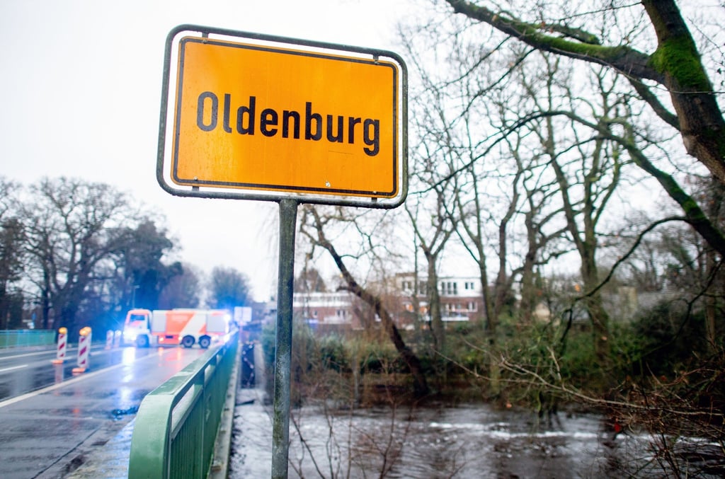 Ein Ortsschild steht am Ortseingang von Oldenburg an einer Brücke über dem Osternburger Kanal, der durch das Hochwasser über die Ufer getreten ist und einen Geh- und Radweg überflutet hat.