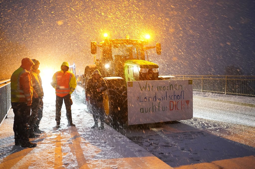 Bauern protestieren mit ihren Traktoren und Plakaten auf einer Brücke über der Autobahn A23.