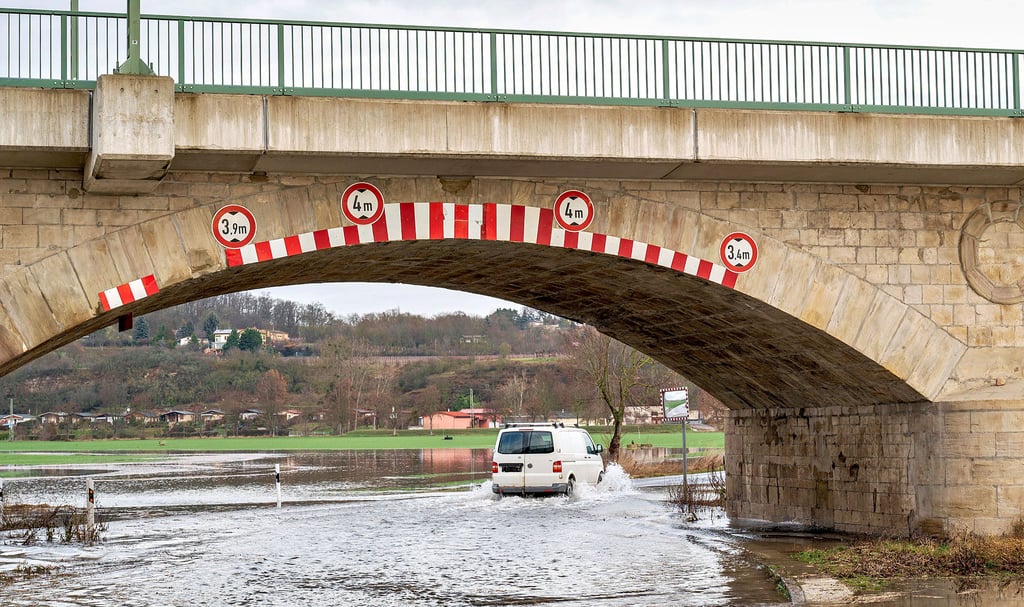Trotz Sperrung fahren Verkehrsteilnehmer  durch die geflutete Senke der Eisenbahnbrücke in Naumburg-Henne.