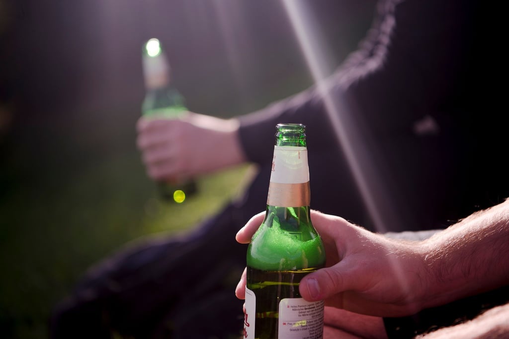 Zwei Männer trinken Bier aus Flaschen.