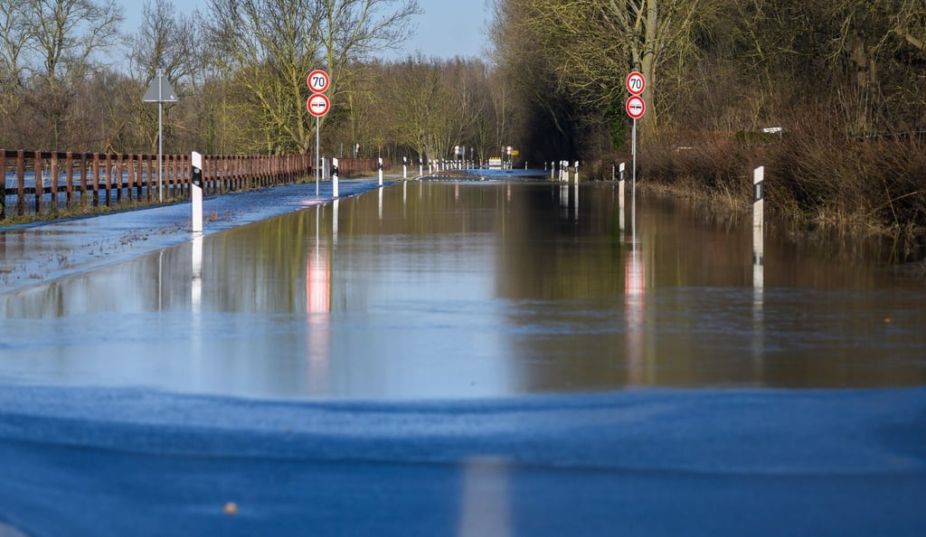 Wasser der über die Ufer getretenen Leine fließt über eine Straße.