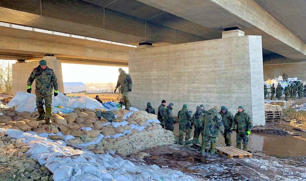 Einsatzkräfte der Bundeswehr verschließen Durchlässe unter der Autobahnbrücke der A71 mit Sandsäcken.