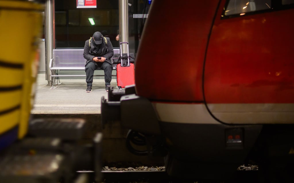 Ein Mann wartet mit Koffer an einem Gleis im Hauptbahnhof Hannover.
