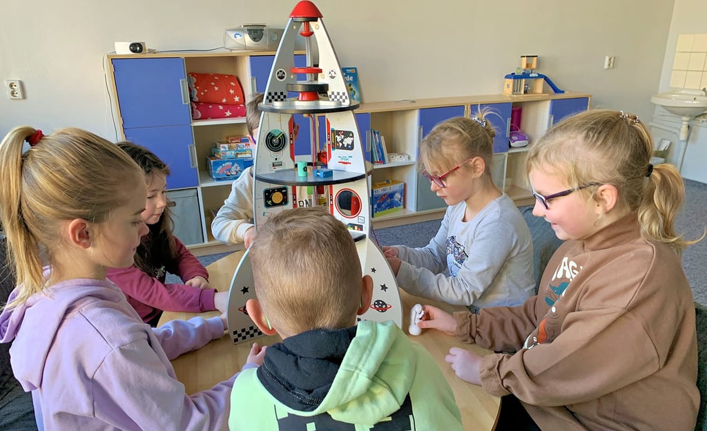 Joelle, Sina, Lennard, Lotta, Mia und Marlo aus der zweiten Klasse in Radegast spielen in einem Hortraum am Modell eines Raumschiffs.