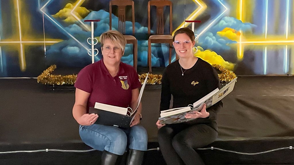 Präsidentin Katja Niedner (l.) und Kassenwartin Anja Beier sitzen auf der Bühne im „Roten Löwen“ und schauen in die dicken Ordner der Vereinschronik.