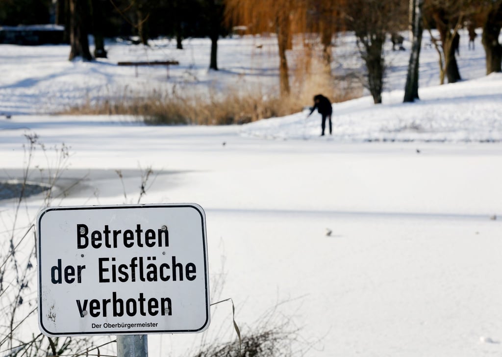 Ein Schild weist auf das Verbot des Betretens eines vereisten Sees hin.