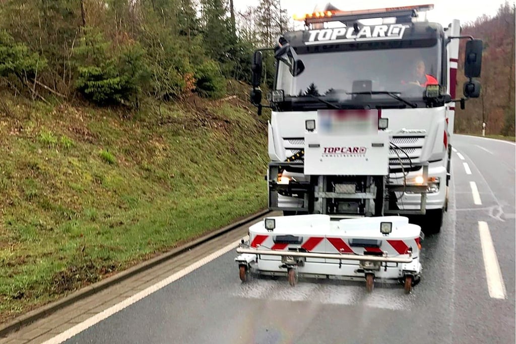 Ein Mitarbeiter der Firma Top Car entfernt eine Ölspur.