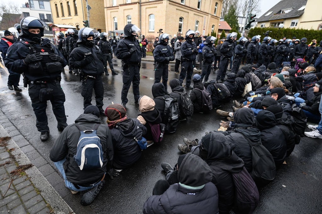 Teilnehmer sitzen bei einer Demonstration des „Göttinger Bündnisses gegen Rechts“ gegen Querdenker und extreme Rechte auf der Straße vor Einsatzkräften der Polizei.