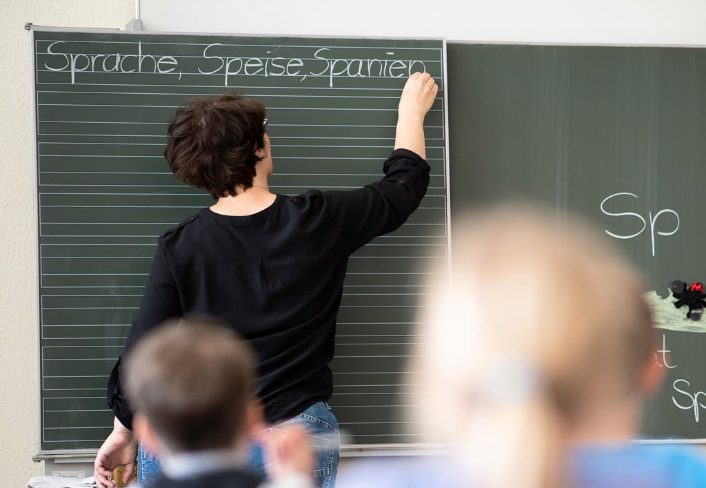 Eine Lehrerin schreibt in einer Schule Worte an eine Tafel.