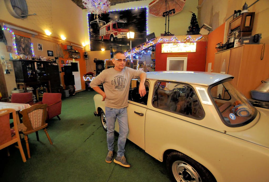Trabi in der guten Stube: Carsten Helbig steht an dem DDR-Fahrzeug, das der absolute „Hingucker“ im urig eingerichteten Saal der einstigen Wethauer Gaststätte „Deutsches Haus“ ist.