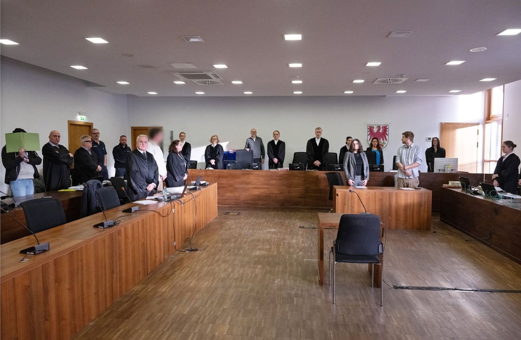 Die beiden Angeklagten (l und 7.v.l) stehen vor Beginn der Verhandlung im Gerichtssaal 8 neben ihren Anwälten.