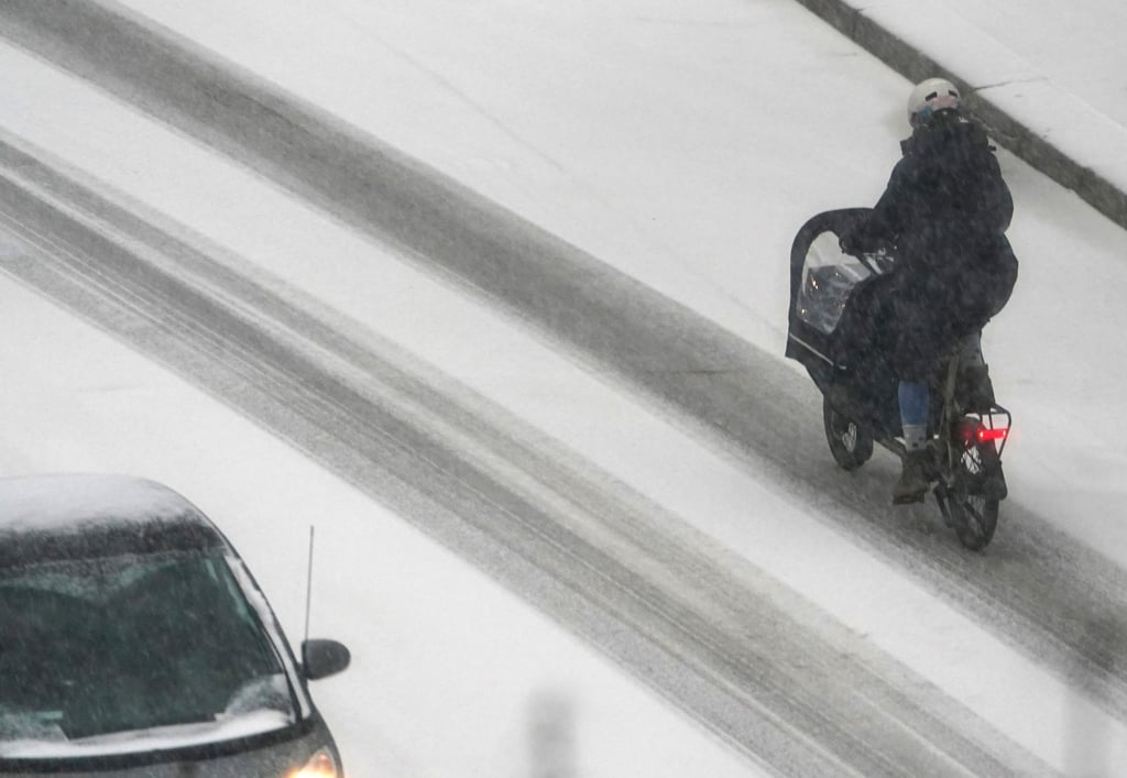 Eine Frau fährt mit einem Lastenfahrrad in Hamburg über eine verschneite Straße.