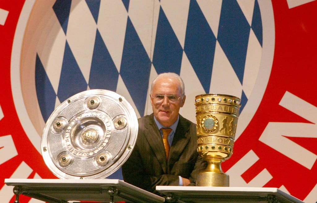 Franz Beckenbauer 2006 zwischen Meisterschale und DFB-Pokal.