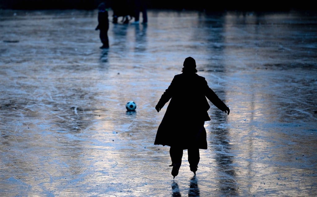 Eine Eisläuferin dreht auf einem zugefrorenen Teich im Johannapark in Leipzig ihre Runden.