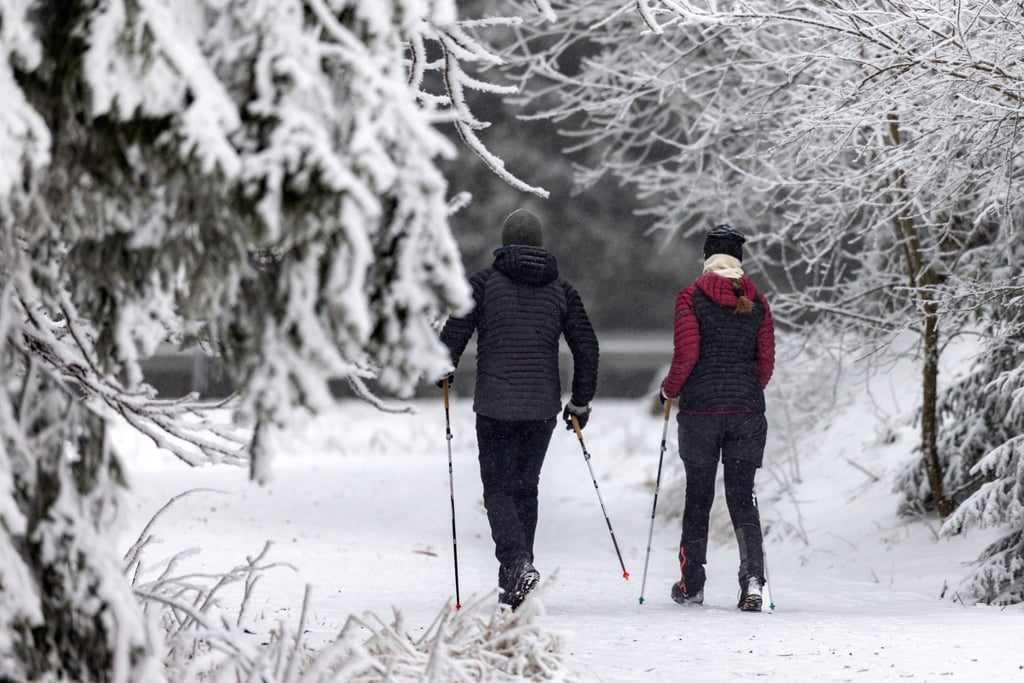 Zwei Nordic Walker laufen am Rondell durch den Schnee.