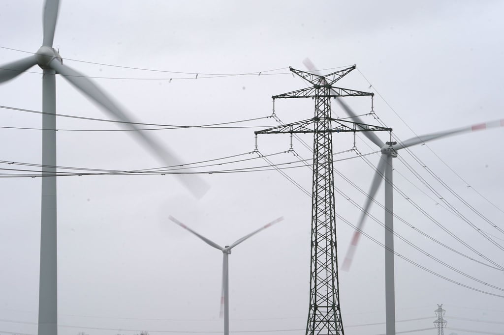 Ein Strommast steht in einem Windpark.