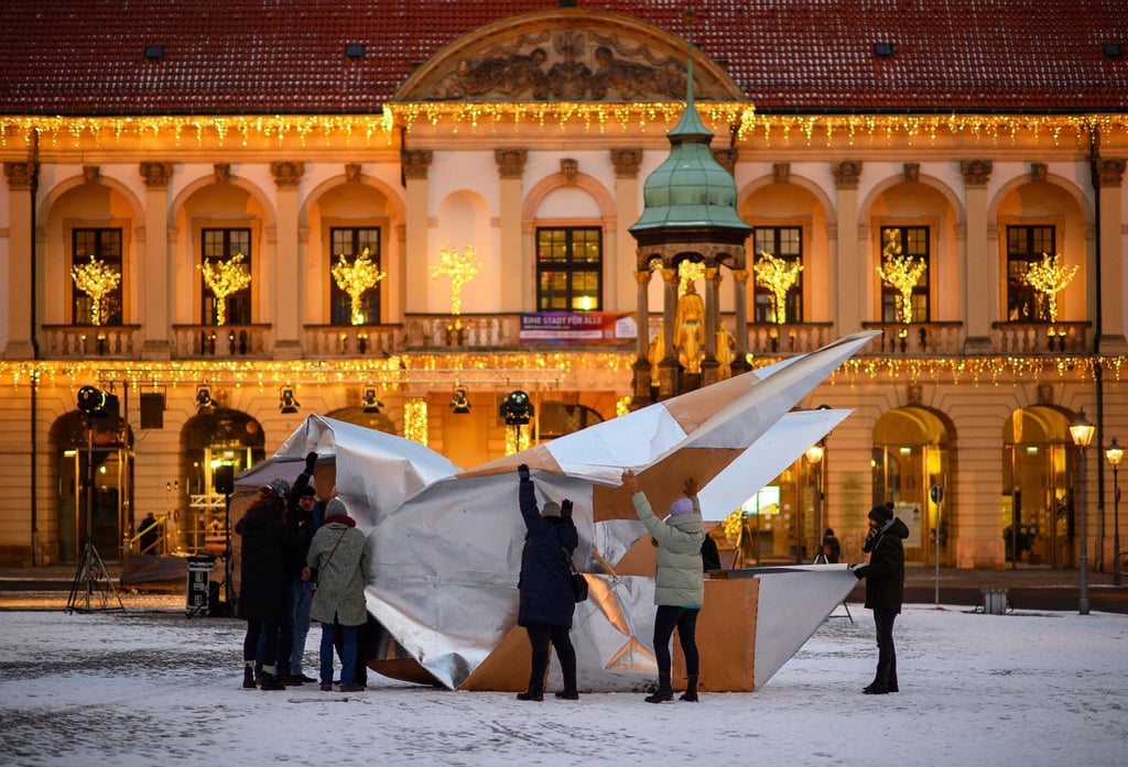 Bürger der Stadt Magdeburg und Mitarbeiter der Arbeiterwohlfahrt (AWO) stellen vor dem Rathaus eine XXL-Friedenstaube aus Milchtütenkarton auf.