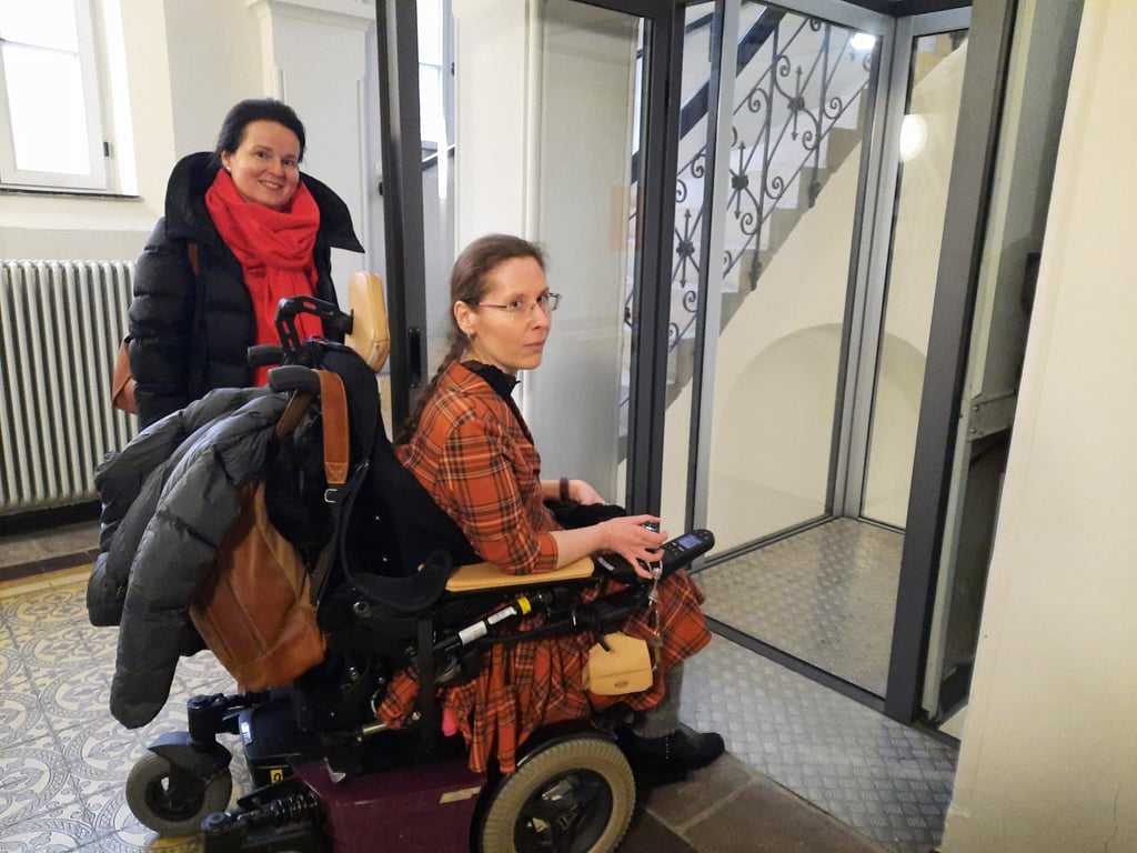 Sandy Scheunpflug hält Nicole Rodegast die Tür zum Aufzug im Weißenfelser Ratsaal auf. Anders können ihn Menschen im Rollstuhl nur schwerlich nutzen.