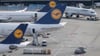 Passagierjets der Lufthansa stehen auf einem Flughafen.