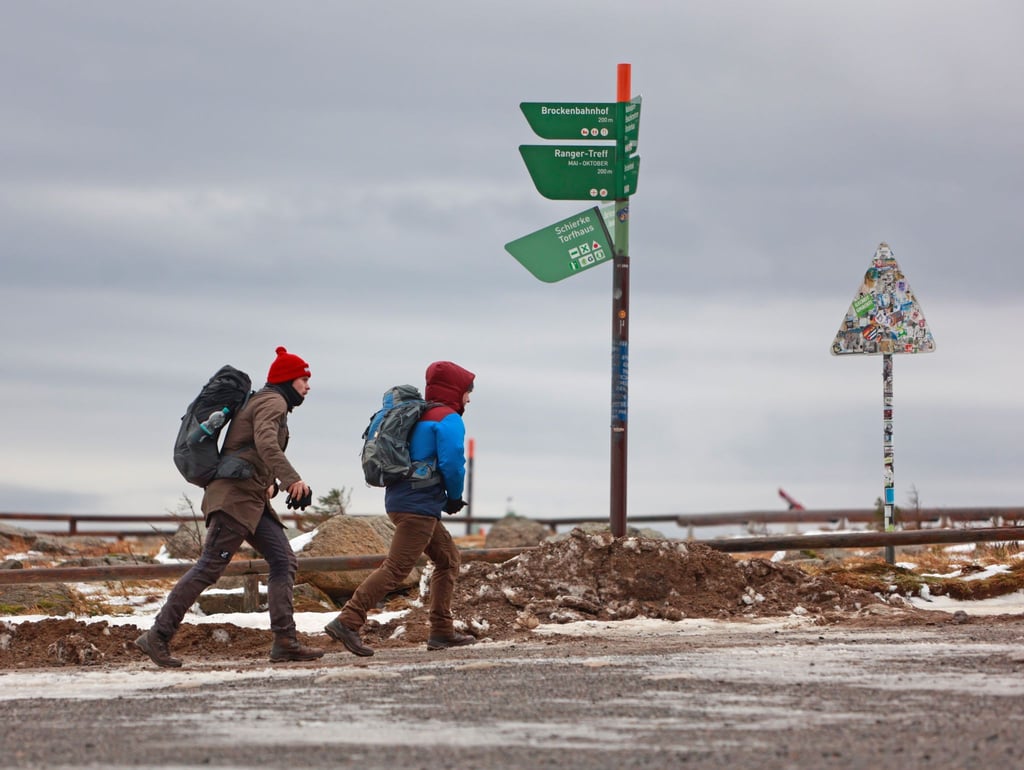 Brockenwanderer gehen bei stürmischen Wind auf dem Brocken entlang.