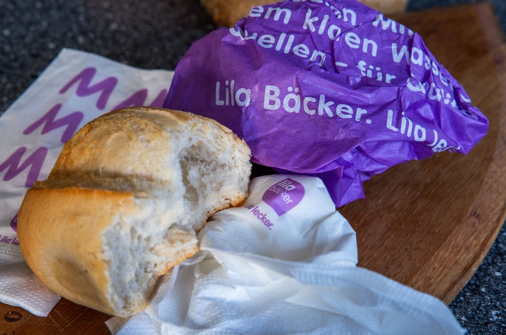 Ein Brötchen aus einer „Lila Bäcker“-Filiale liegt auf einem Frühstücksbrett.