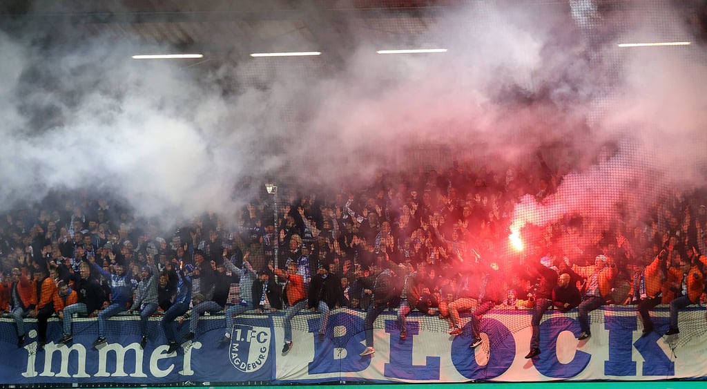 Fans des 1. FC Magdeburg mit einer bengalischen Fackel beim DFB-Pokal-Spiel in Kiel.
