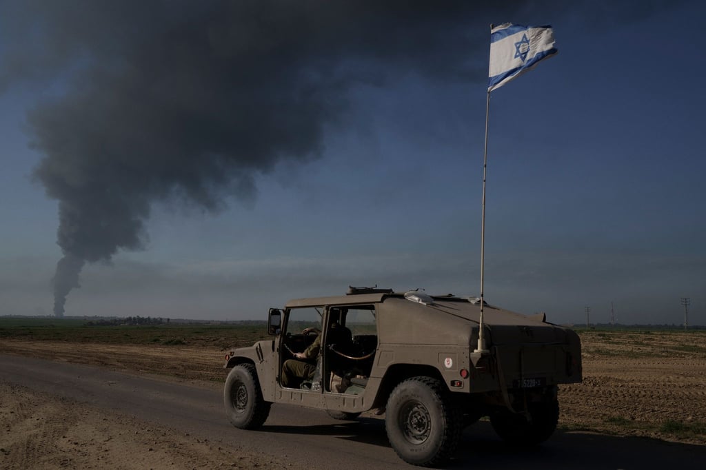Israelische Soldaten in der Nähe der Grenze zwischen Israel und dem Gazastreifen, während in dem Küstengebiet Rauch in den Himmel steigt.