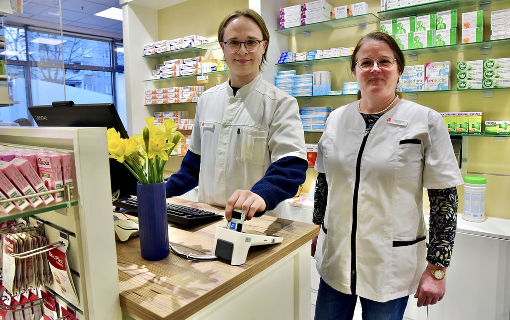 Apothekerin Isolde Grabner (rechts) und Mitarbeiter Lucas Kranhold lesen am neuen Lesegerät für das E-Rezept die Krankenkassenkarte des Kunden aus.