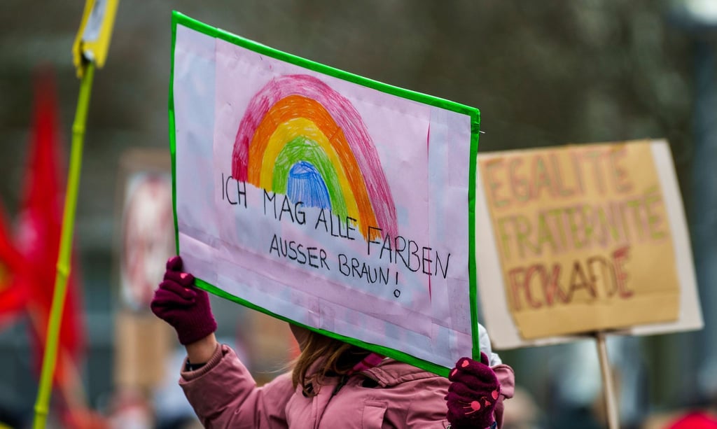 Ein Plakat „Ich mag alle Farben außer Braun!“ wird auf einer Kundgebung hochgehalten.