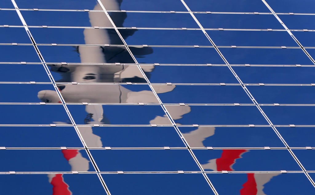 Ein Windrad spiegelt sich in einer Solar-Anlage.