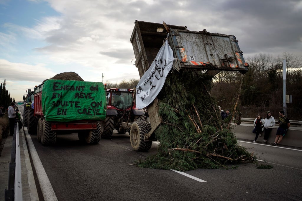 Landwirte kippen Zweige und Äste auf die Fahrbahn, während sie eine Autobahn in der Nähe von Lyon blockieren.