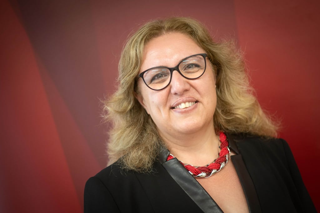 Özlem Ünsal (SPD), Senatorin für Bau, Verkehr und Stadtentwicklung, steht vor einer roten Wand.
