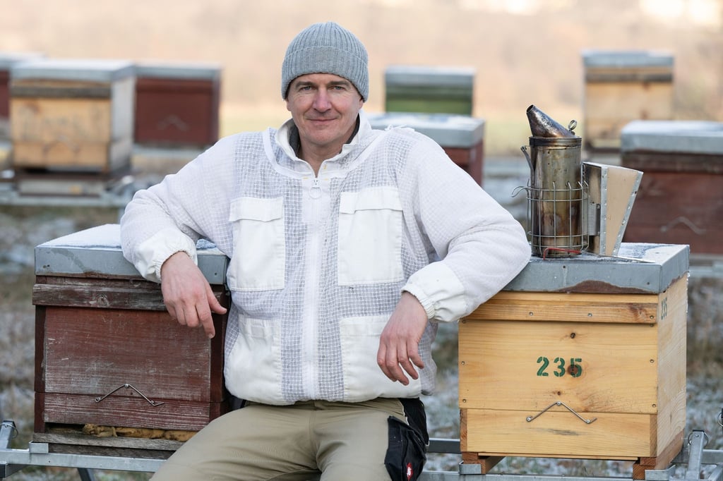 Rico Heinzig, Imker, sitzt zwischen seinen Bienenkästen.