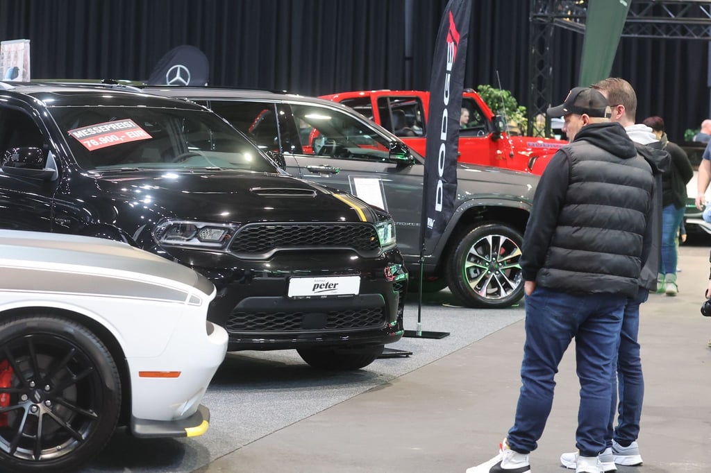 Besucher stehen zwischen Autos in einer Messehalle auf der Automobil Messe Erfurt.
