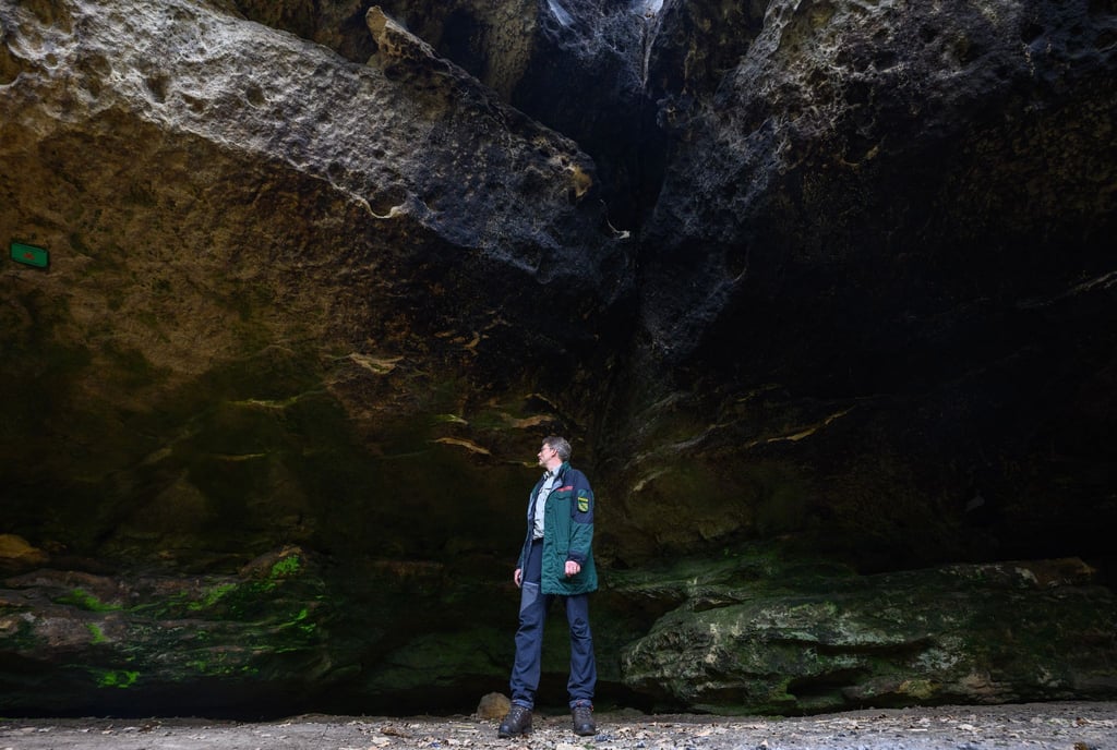 Ein Mitarbeiter der Nationalparkverwaltung Sächsische Schweiz begutachtet eine Boofe.
