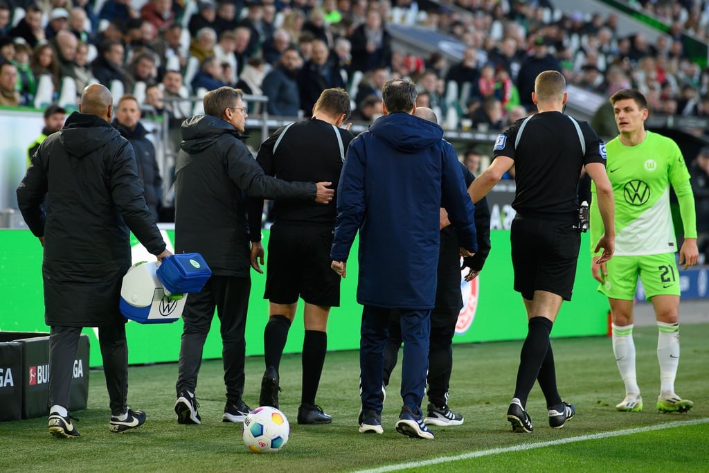 Schiedsrichter-Assistent Thorben Siewer (M) wird vom Platz begleitet.