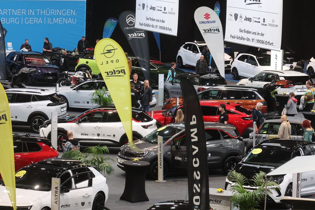 Besucher stehen zwischen Autos in einer Messehalle auf der Automobil Messe Erfurt.