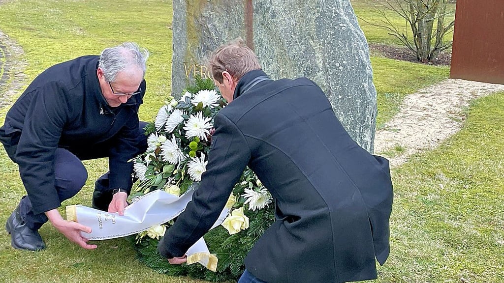 Martin Hering (l.) und Thomas Wendler legen am Gedenkstein auf dem Gelände des AWO-Fachkrankenhauses in Jerichow ein Gebinde nieder.