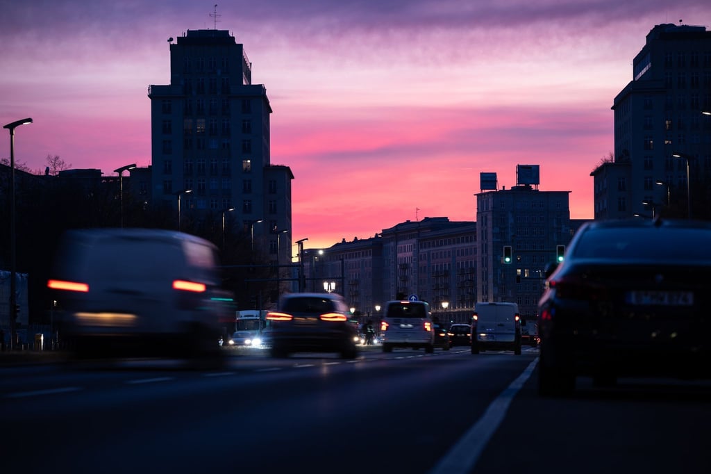 Autos sind bei Sonnenaufgang auf einer Straße unterwegs.