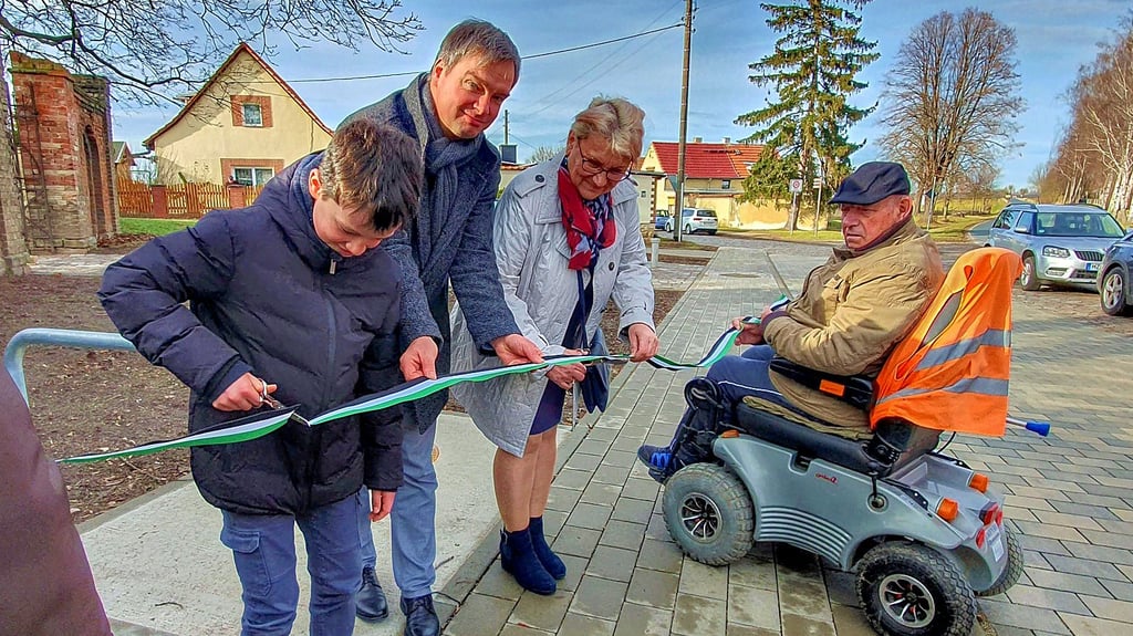 Wilslebens Ortsbürgermeisterin Kathrin Ryssel, Oberbürgermeister Steffen Amme und dessen Sohn Johannes durchschneiden das symbolische Band.