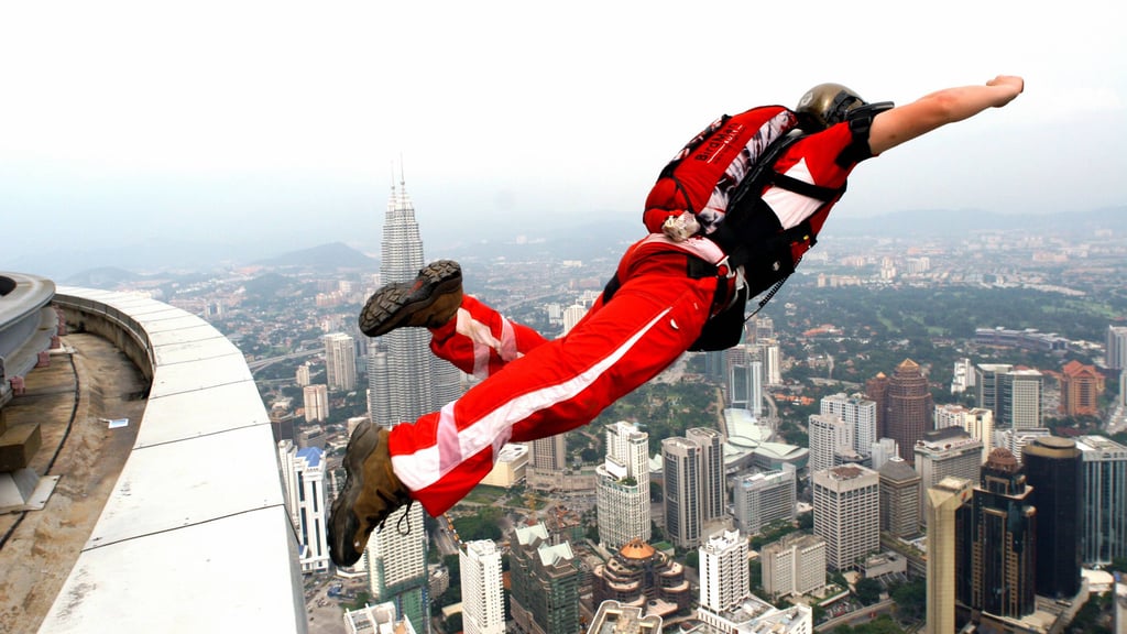 Ein Basejumper springt von einem Hochhausdach.