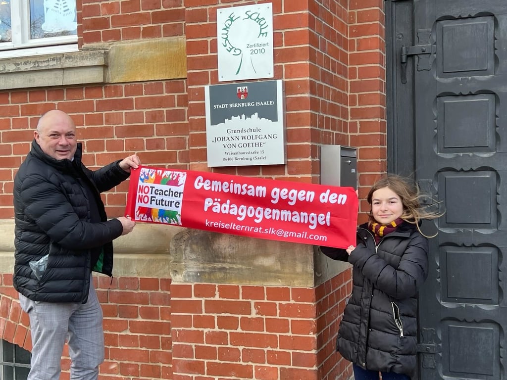 Maik Laue, Elternsprecher der Goethe-Grundschule in Bernburg, hängt ein Plakat im Kampf gegen den Lehrermangel auf.