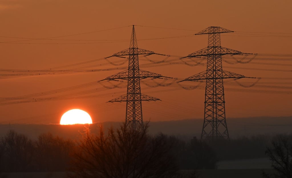 Die Sonne geht hinter Strommasten auf.