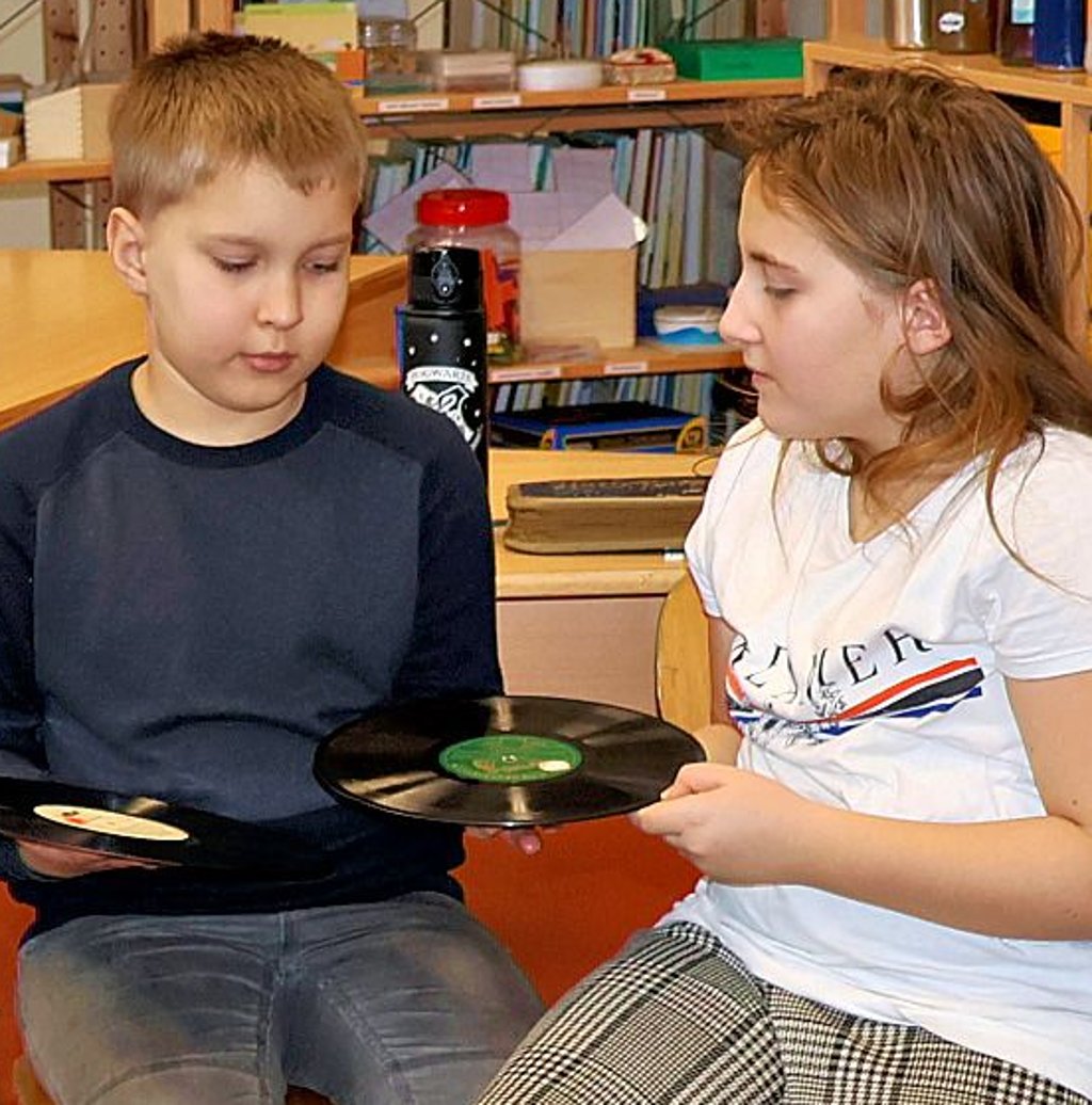 Kinder in Kamern betrachten Schallplatten: Wie darauf wohl Musik aufgenommen wurde?