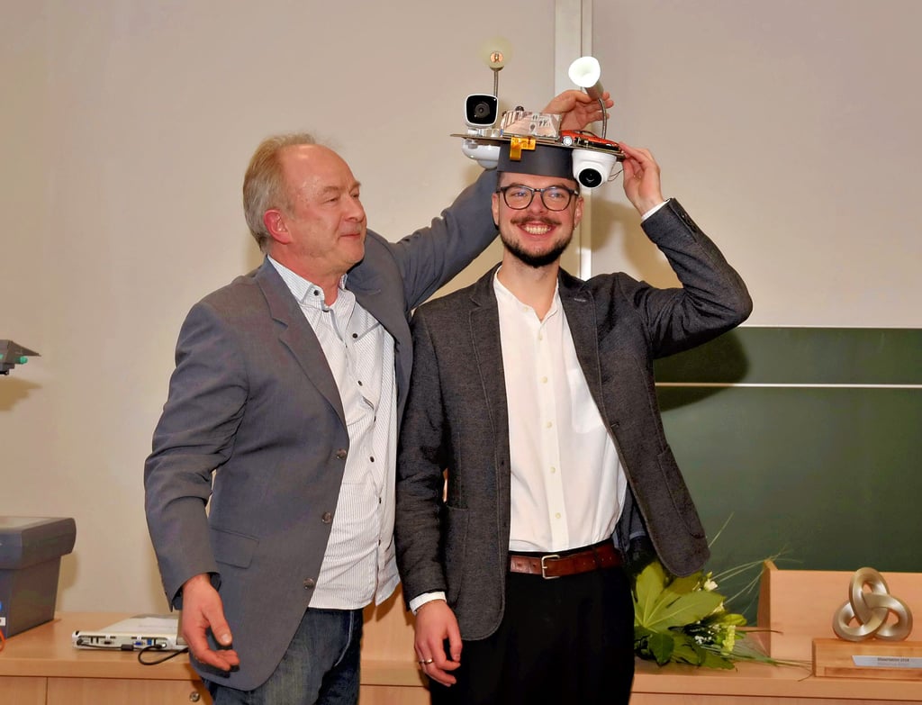Professor Ingo Chmielewski überreicht Ivan Matveev passend zum Thema seiner Doktorarbeit ein passendes Präsent für die erfolgreiche Verteidigung.