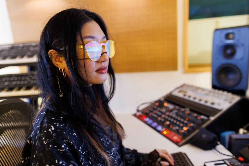 Musikerin Rania Kim zwischen Displays, Anlagen und Instrumenten in einem Studio in Berlin.
