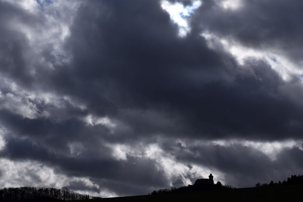 Starker Wind treibt dunkle Wolken am Himmel über der Wachsenburg.