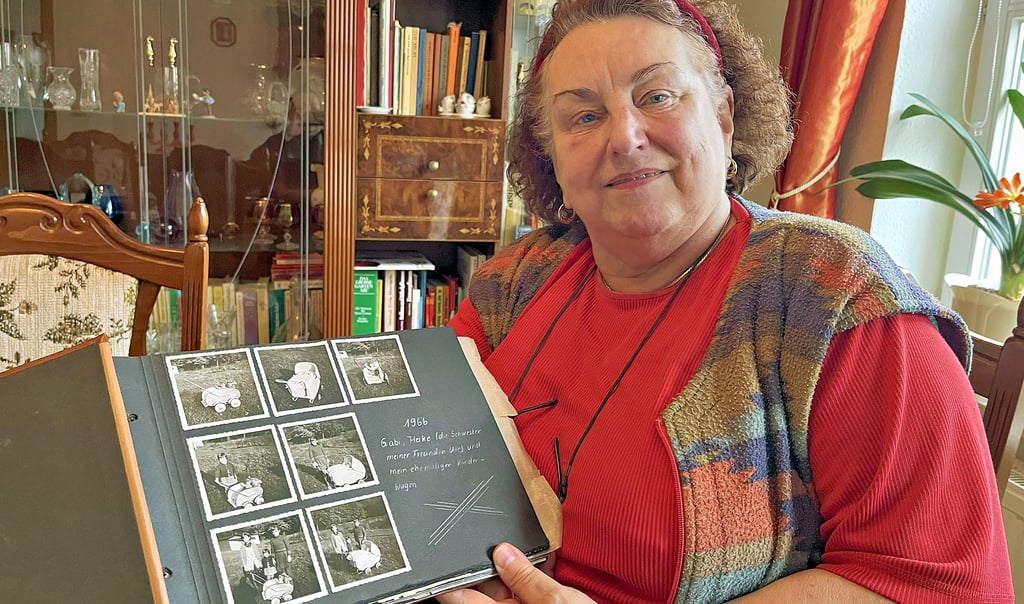 Silvia Spittel mit einem Fotoalbum aus ihrer Kindheit. Der eigene Kinderwagen, der damals noch als Puppenwagen diente, steht heute im Heimatmuseum in Tangerhütte.