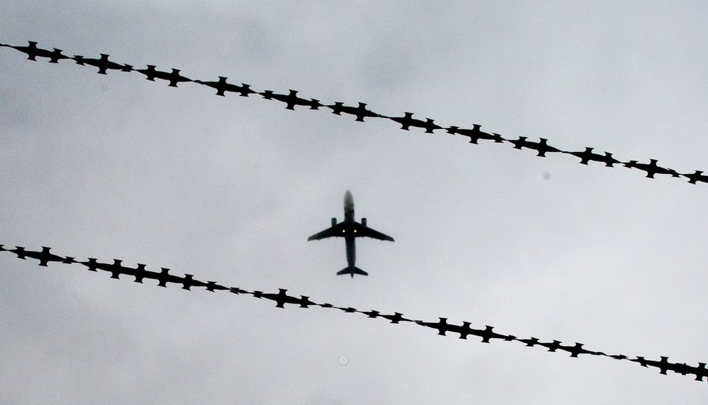 Ein Flugzeug ist hinter dem Stacheldraht zu sehen.