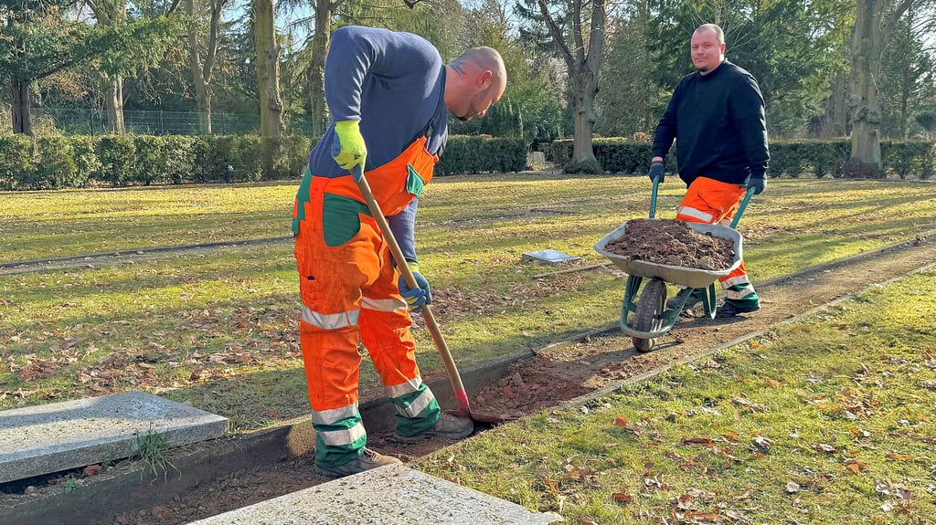 Die Stala-Mitarbeiter Martin Wurzendorf (links) und Alexander Näwie schachten die Wege auf dem Ehrenfriedhof in Halberstadt aus.